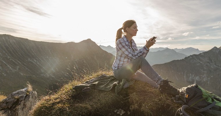woman staring at her phone in nature